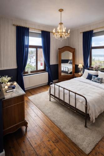 a bedroom with a bed with blue curtains and a chandelier at Maison de Maître in Liège