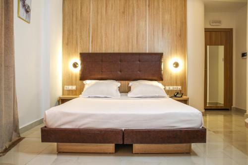 una camera da letto con un grande letto con testiera in legno di Hotel Opera a Rouiba