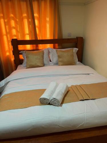 a bed with two rolled up towels on it at Gracious homes in Narok