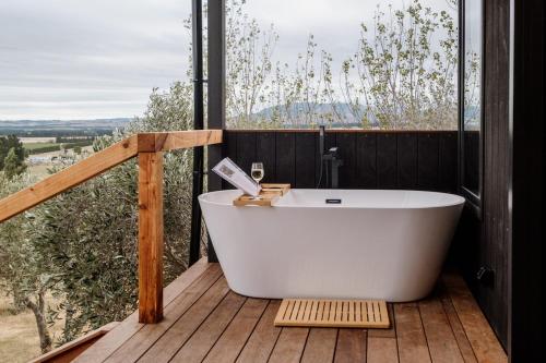 a bath tub on a wooden deck with a view at Casa Olea in Waipara