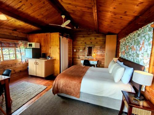 a bedroom with a bed in a log cabin at Tegwaan's Nest B&B in Mooiriver