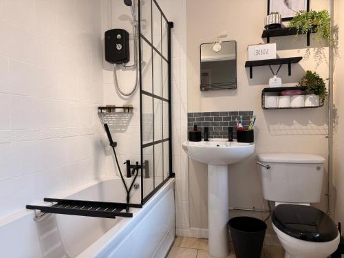 a bathroom with a sink and a toilet and a shower at 2 Bedroom House By Travel Lets Holiday Homes Derry With Garden in Derry Londonderry