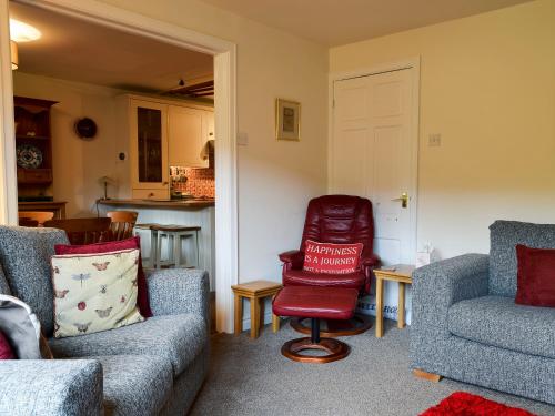 a living room with two chairs and a red chair at Fell View in Kettlewell