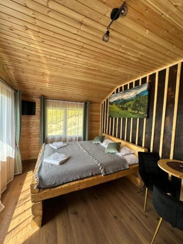 ein Schlafzimmer mit einem Bett in einer Blockhütte in der Unterkunft Colnic Tiny House in Măgura