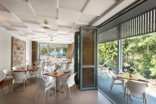 a dining room with tables and chairs and large windows at Heart Hotel and Gallery Whitsundays in Airlie Beach