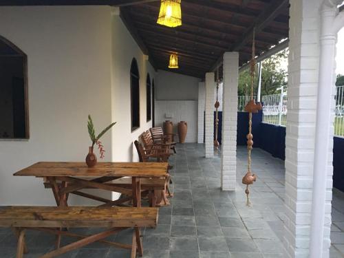 a porch with wooden tables and chairs and a ceiling at Pousada de Santo Antônio in Ilha de Boipeba