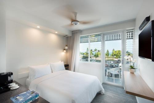 a bedroom with a white bed and a large window at Heart Hotel and Gallery Whitsundays in Airlie Beach