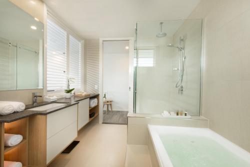 a bathroom with a tub and a shower and a sink at Heart Hotel and Gallery Whitsundays in Airlie Beach