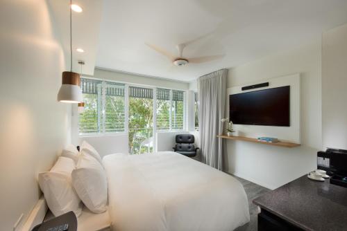 a bedroom with a television and a bed at Heart Hotel and Gallery Whitsundays in Airlie Beach