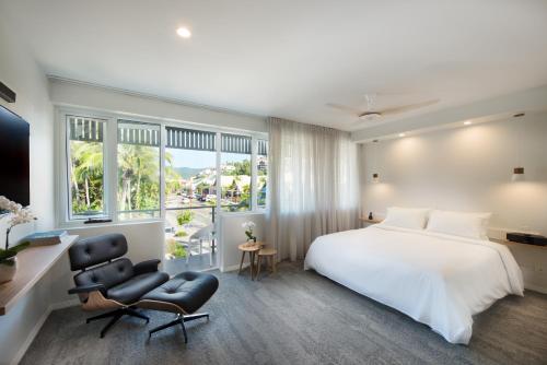 a room with a bed, chair, desk and a window at Heart Hotel and Gallery Whitsundays in Airlie Beach