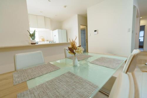 a dining room table with a vase of flowers on it at The Kabira 川平湾に一番近いヴィラ 滞在中レンタカー無料 The closest private villa to Kabira Bay! Free car rental in Ishigaki Island