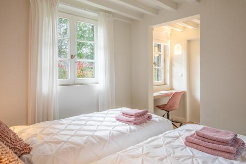 a white bedroom with pink towels on a bed at Boonackere Cottage in Oosterzele