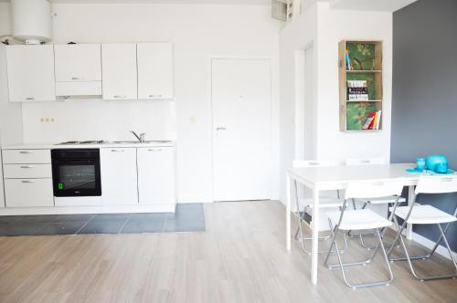 ブリュッセルにあるFlat Sympa next Grand Placeの白いキャビネット、テーブルと椅子付きのキッチンが備わります。