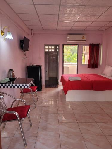 a bedroom with a red bed and a table and chairs at ลพบุรีทาวน์ Lopburi Town in Lop Buri