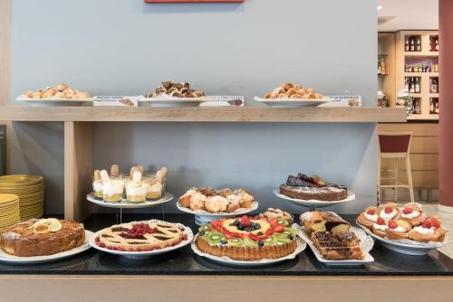 a counter with many different types of cakes and pastries at Idea Hotel Torino Mirafiori in Turin