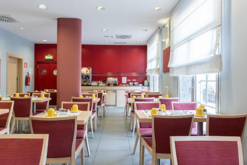 a restaurant with tables and chairs and red walls at Idea Hotel Torino Mirafiori in Turin