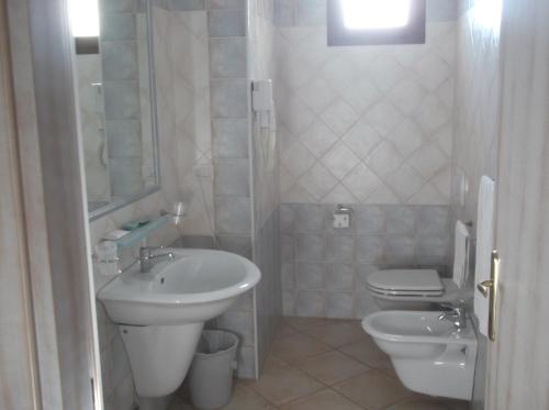 a white bathroom with a sink and a toilet at Hotel Tabby in Golfo Aranci