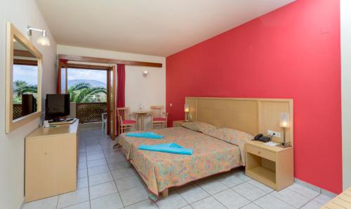 1 dormitorio con cama y pared roja en Dessole Malia Beach - All Inclusive, en Malia