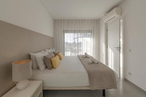 a white bedroom with a bed with a window at Silver Coast Haven in Coto