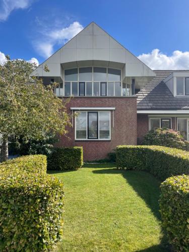 a house with hedges in front of it at Gastenverblijf Buitenplaats Wergea contactloos inchecken in Naarderburen