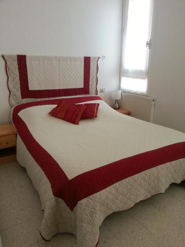 a large bed with a red and white comforter at O'Paloma - appartement T2 au port - Parking - Terrasse in Saint-Cyprien-Plage
