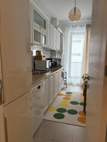 a kitchen with white cabinets and a rug on the floor at Safirului apartment in Bragadiru