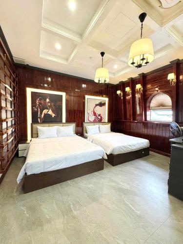 a bedroom with two beds and two chandeliers at SALA HOTEL HUE in Hue