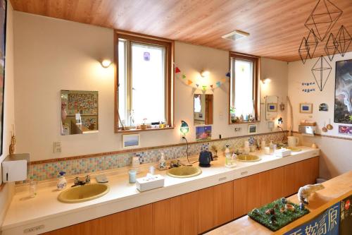 a bathroom with three sinks and two mirrors at Guesthouse Hoshizora no Akari in Matsumoto