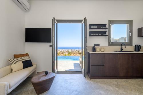 a living room with a couch and a kitchen at Koniko Santorini Private Pool Villas in Vóthon