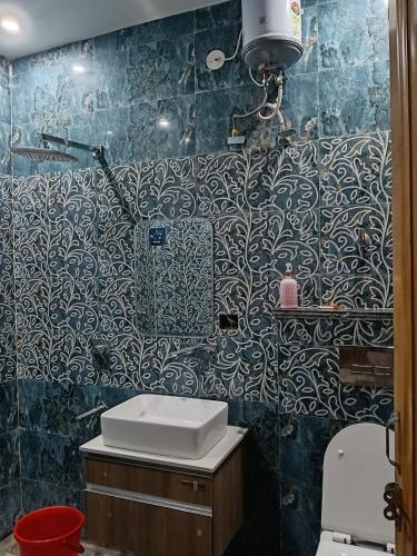 a bathroom with a sink and a blue tiled wall at Zora apartment in Rohtak