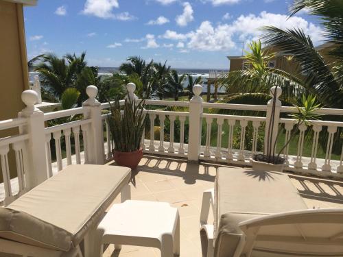 a balcony with two chairs and a white fence at Palmar Bay - Beachside Villa in Palmar