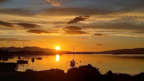 a sunset over a body of water with boats at An Cala in Connel