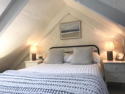 a bedroom with a white bed with two pillows at Manderley Cottage, Mousehole in Mousehole