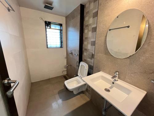 a bathroom with a sink and a toilet and a mirror at Aarna Villa nr Valvan Dam in Lonavala