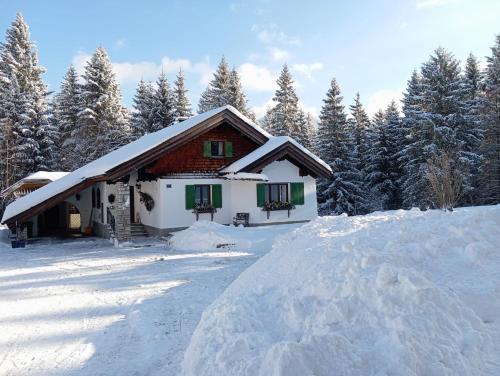 a house covered in snow with trees in the background at Ferienhaus Wimmer in Faistenau