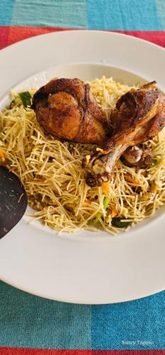 a white plate of food with noodles and meat at lake paradise cabana in Tissamaharama