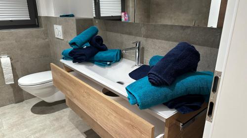 a bathroom with blue towels on a sink and a toilet at Bergperle in Grächen