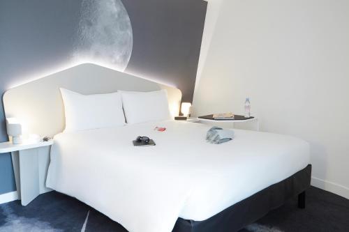 a bedroom with a white bed with two shoes on it at ibis Styles Paris Charles de Gaulle Airport in Roissy-en-France
