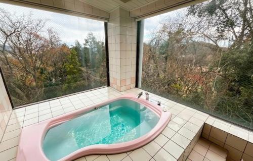 a pink bath tub in a bathroom with windows at ホテル アルファ in Iizaka