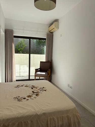 a bedroom with a bed and a chair and a window at Point de Mire in Rivière Noire