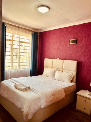 a bedroom with a bed with a red wall at Tranquille Homestay near JKIA Airport & SGR Station Nairobi in Nairobi