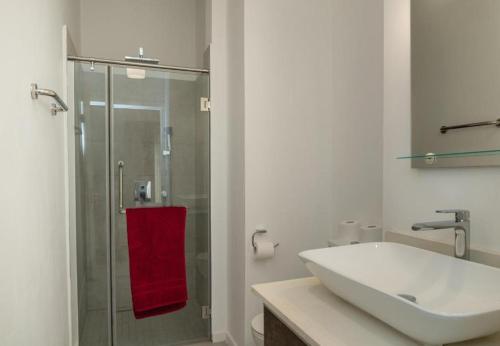 a bathroom with a sink and a shower with a red towel at Point de Mire in Rivière Noire