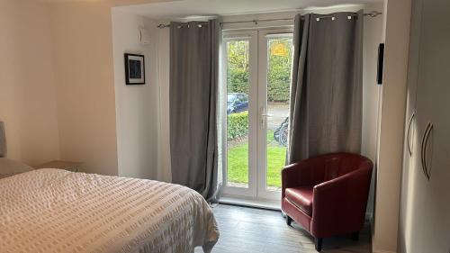 a bedroom with a bed and a chair and a window at 2 bed room , ensuite Flat close to Heathrow, Windsor , Langley in Langley Marish