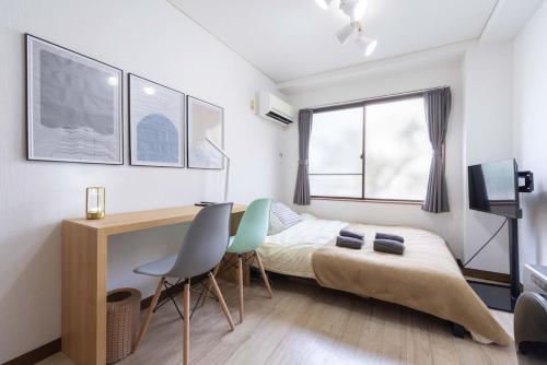 a bedroom with a bed and a desk and chairs at Kunark KM102 Stay in Kokubunji