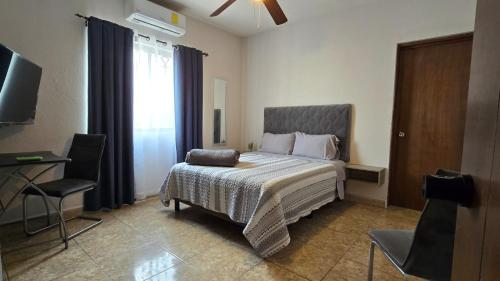a bedroom with a bed and a chair and a television at Habitacion Cedro in Saltillo