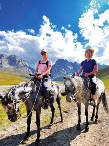 two people riding horses on a dirt road at Kel-Suu Kyrgyzstan Yurt Camp in Kol-Suu