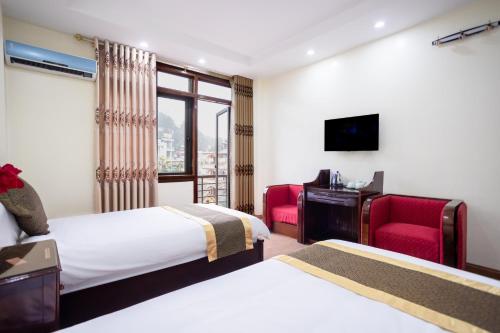 a hotel room with two beds and a desk and a television at Sao Mai Bac Ha Hotel in Bắc Hà
