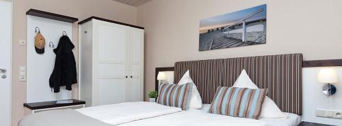 a bedroom with a bed with white sheets and pillows at Hotel Küstenklang - FREE Parking by ANS in Carolinensiel