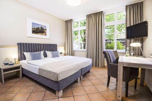 a hotel room with a bed and a desk at Hotel Küstenklang - FREE Parking by ANS in Carolinensiel