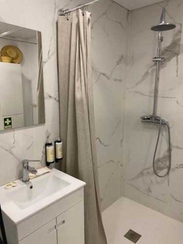a bathroom with a sink and a shower with a shower curtain at Casa da Zéfinha - STUDIO in Cinfães